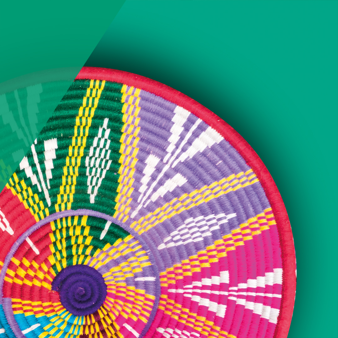 Close-up of a colorful woven basket with geometric patterns in purple, green, yellow, pink, and white on a teal background.