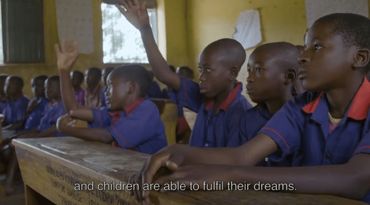 Children in a classroom raising their hands, eager to learn.