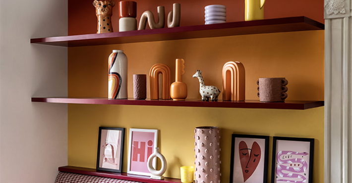 Modern wall shelves displaying colorful ceramic vases, abstract decor, a giraffe figurine, and framed artwork in a stylish, contemporary room.