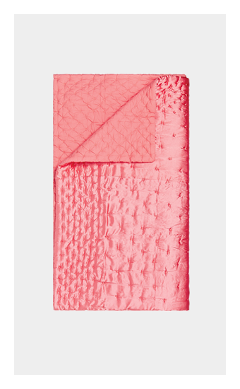 A crinkled pink quilted throw blanket.