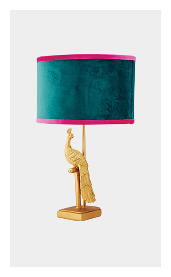 A decorative lamp with a golden peacock base and a teal and pink velvet shade.