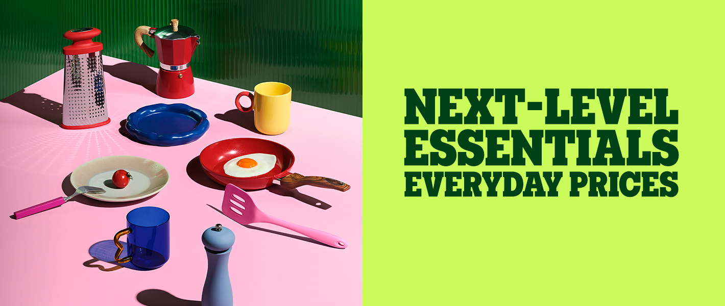 Colorful kitchen essentials including a grater, coffee pot, mugs, plates, and utensils on a pink surface, with the text "Next-level essentials, everyday prices.