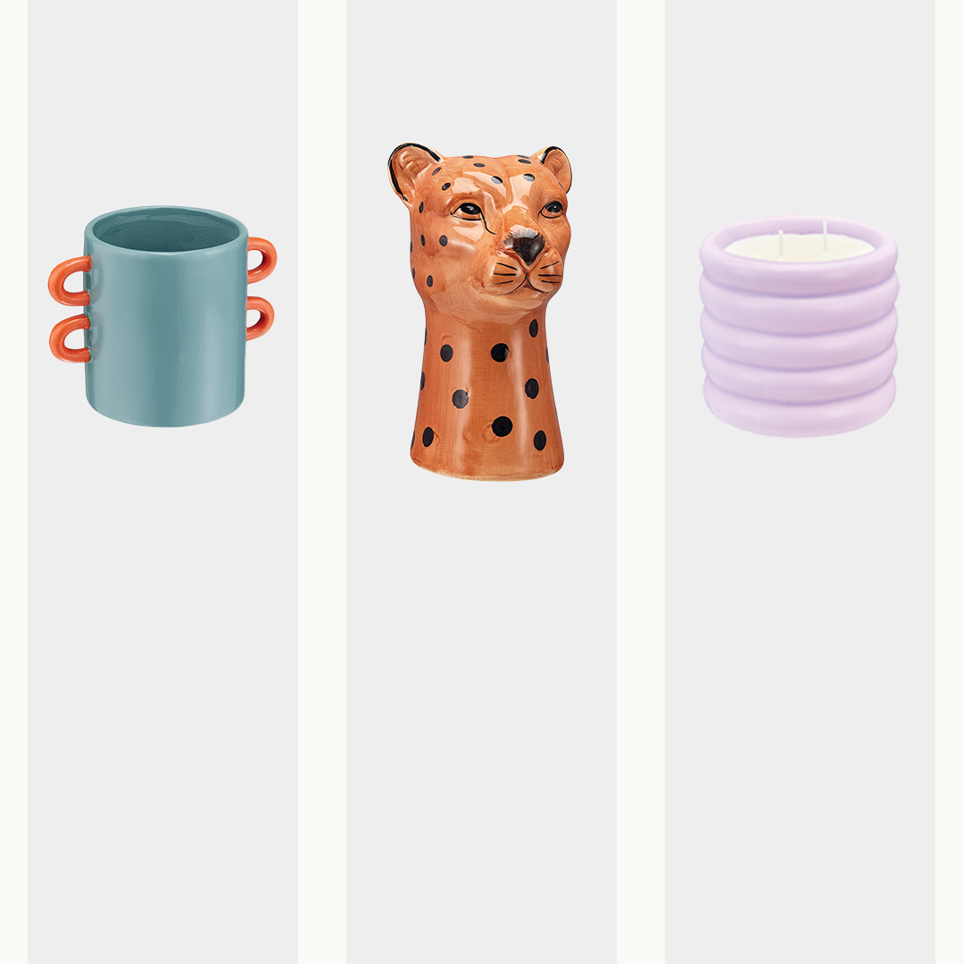 Colorful home decor items: a blue mug with orange handles, a spotted cheetah head vase, and a ribbed lavender candle.